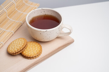 Cozy morning scene with a cup of coffee, tea, and two cookies on a wooden table. Warm natural light creates a calm and relaxing atmosphere, perfect for lifestyle, breakfast, or cozy home concepts.