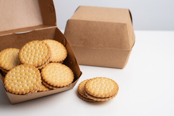 Cookies in a craft box on a light background. Homemade cookies in eco-friendly packaging. Composition for branding, delivery, or catering concepts. Sweet snack.
