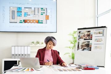 Asian designer woman writing on notebook create new idea while working in studio office