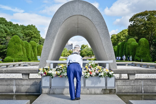 A man bows before flowers at Hiroshima Peace Memorial Park