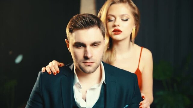 Sexy couple beauty woman hugging with man, adult girl seduces in dark room full smoke guy. blonde girl red lips whispers in male ear. fashion model blonde hair evening dress. Fantasy lady vampire