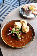 Close-up top view of traditional Czech goulash with Karlovy Vary dumplings, served on a wooden table in a restaurant. The rich colors and textures of the dish highlight the warmth and authenticity