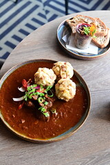Close-up top view of traditional Czech goulash with Karlovy Vary dumplings, served on a wooden table in a restaurant. The rich colors and textures of the dish highlight the warmth and authenticity