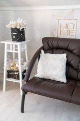 Christmas interior of a bright living room. The attic. A white Christmas tree with a brown sofa. Daytime.