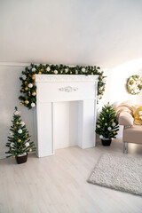 Christmas garland of green fir with gold and white balls on the fireplace in the bright living room