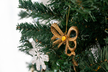Golden bow on the branch of the Christmas tree. Christmas decorations.