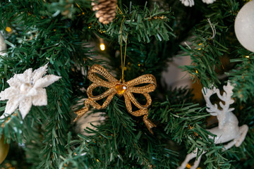 Golden bow on the branch of the Christmas tree. Christmas decorations.