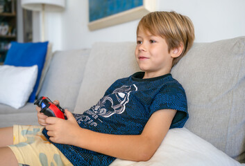 Child boy playing at home with game consola at home.