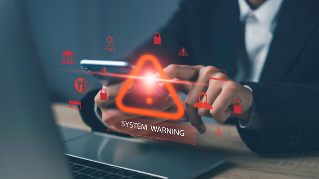 System warning alert with red exclamation triangle and cybersecurity icons on smartphone and laptop screen, representing data breach risk, malware threats, and digital security issues in business.