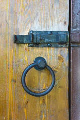 Wooden door with metal bolt and ring knocker. Traces of corrosion are visible