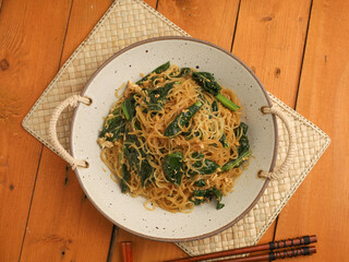 Fried rice noodles and vegetables on wooden background