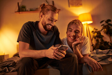 Joyful gay couple shares laughter while looking at their phone after a romantic date night