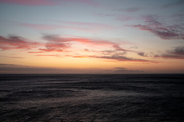 The sea at dusk is illuminated by a brilliant sunset glow.