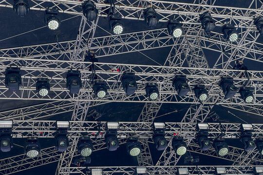 Complex Array of Moving Head Stage Lights, metallic truss system structure for professional event and concert lighting concept, dark background for theatrical design