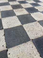 stone chessboard embedded in concrete with engraved coordinates, showing textured surface and contrast of black and white squares. Ideal for design backgrounds, strategy concepts, or game-themed visua
