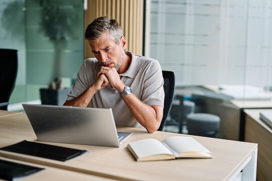 Portrait of a young businessman  or a young entrepreneur or a student having a headache and being under pressure and stress  working on tablet or laptop  computer working in office