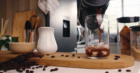 Glass, kitchen and pour ice coffee with french press for drink preparation, espresso or morning brew. Caffeine, jar and cold beverage with cubes, liquid and refreshment in container on table at home - Powered by Adobe