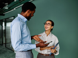 Portrait of young businesswoman and businessman using a tablet having a meeting or presentation and...