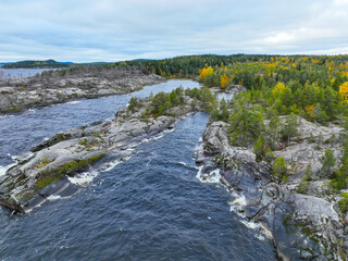 High angle view of a wide channel of dark water flowing between heavily fractured rocky shores...