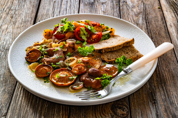 Fried saffron milk cap mushrooms with fresh salad and bread on wooden table	