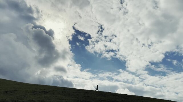 silhouette of a man walking on hillside under cloudy sky, xinjiang, china