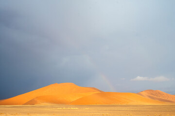 Rolling desert dunes near North Windhoek, Namibia, stretch beneath a dramatic cloudy sky
