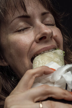 A person bites shawarma. Girl eats fast food. Mental health. Food industry. Victim of advertising. Binge stress. Uncontrolled gluttony. Eat with appetite. Skin texture. Human greed. Sin of gluttony.