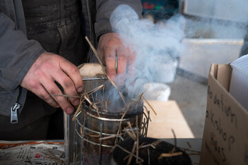 Close-up of a beekeeper preparing a smoker with straw at Dancing Bee Farm in Port Hope, Ontario, Canada, capturing the process of natural hive management and sustainable beekeeping