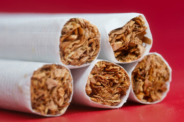 Extreme macro of five modern cigarettes, packed tobacco ends on bold red background; smoking hazard web banner with high‑res detail and copy space. Photo