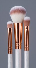 Three cosmetic brushes; white handles and soft, blush-tipped bristles