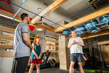 Personal trainer guiding diverse adult group during gym workout
