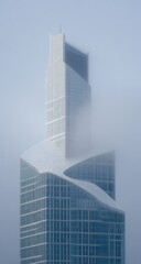Modern skyscraper pierces through ethereal fog under a hazy sky.