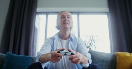 Emotional senior man wins single player video game with joysticks at home - Powered by Adobe