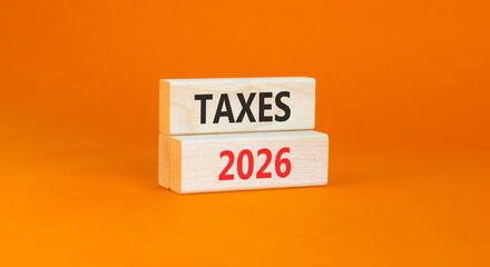 Taxes 2026 new year symbol. Concept words Taxes 2026 on beautiful wooden blocks. Beautiful orange paper background. Business and taxes 2026 new year concept. Copy space.