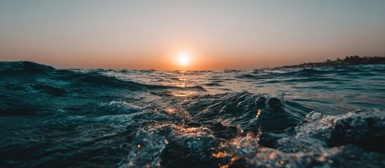 Calm ocean waves at sunset reflect the warm orange sky.