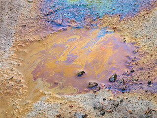 A gasoline stain in a puddle on the ground