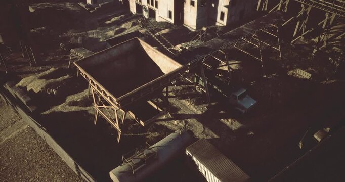 Faded structures stand solemn against a dusky sky, showcasing an abandoned industrial site. Broken machinery hints at a once bustling environment now lost to time.