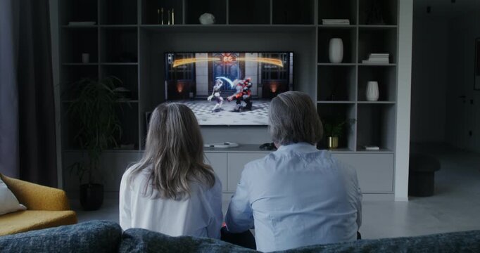 Elderly man and woman playing a video game, rear view - Powered by Adobe