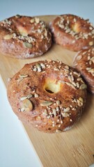 Freshly baked bagels topped with mixed seeds on a wooden board