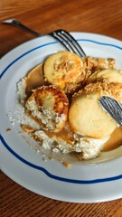 Delicious cottage cheese pancakes served with cream and caramel sauce on a white plate. Concept of homemade breakfast, comfort food, and traditional dessert enjoyment