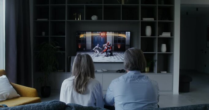 Gray haired man and woman playing video game at home