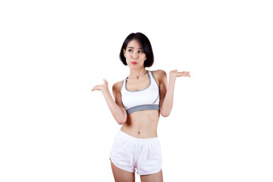 Fit young woman in sportswear standing with a confused expression and shrug gesture on pink background, representing uncertainty, decision, or choice concept.