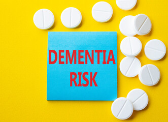 Dementia Risk symbol. Concept word Dementia Risk on blue note. Beautiful yellow background with pills. Medicine and Dementia Risk concept. Copy space