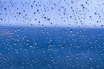 Gotas de lluvia cayendo sobre un cristal con el mar Mediterr&aacute;neo de fondo, creando una textura natural y atmosf&eacute;rica.