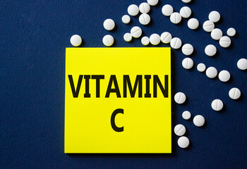Vitamin C symbol. Concept word Vitamin C on yellow note. Beautiful deep blue background with pills. Medicine and Vitamin C concept. Copy space