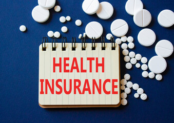 Health Insurance symbol. Concept word Health Insurance on notebook. Beautiful deep blue background with pills. Medicine and Health Insurance concept. Copy space