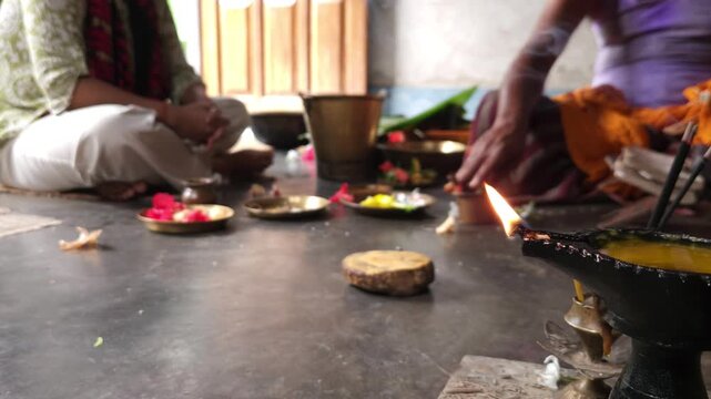 Close-up of Shivling pooja with milk, flowers, and bael leaves being offered. Indian people performing sacred havan on the occasion of Mahashivratri, offering ghee. Focused on foreground