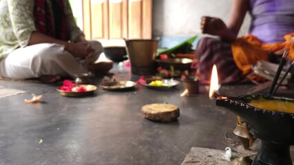 Close-up of Shivling pooja with milk, flowers, and bael leaves being offered. Indian people performing sacred havan on the occasion of Mahashivratri, offering ghee. Focused on foreground