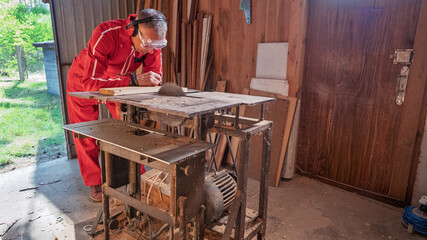 A man examines a part on a woodworking machine.