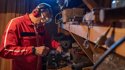 A man in work clothes uses a vice.